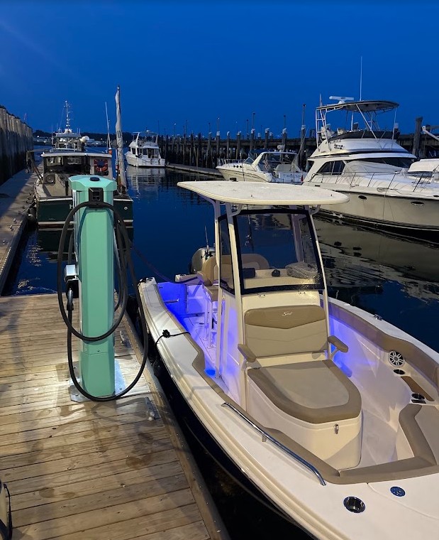 Electric boat charging at a dock at night in Portland